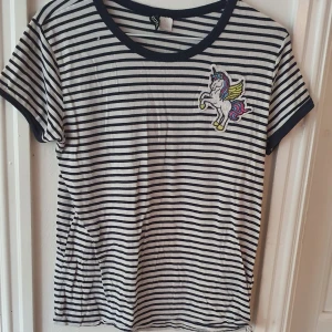 Randig tshirt med enhörning - Marinblå- och vitrandig t-shirt med en enhörningspatch från H&M ⭐ väldigt stretchigt material vilket gör den väldigt bekväm. Storlek M :) Lite sliten men bra skick. Säljs då den inte längre används. Kontakta vid frågor/intresse 💜 frakt inräknad