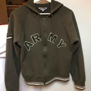 Jättefin zipup - Säljer en jättefin zipup som jag köpt här på Plick! Den är jättefin men har inte använt den så mycket å därför säljer jag den😊 Den är i en militärgrön färg med vita detaljer❤️ Tröjan är i använt skick å är absolut fortfarande användbar! Om nån vill ha mer foton så kan jag absolut skicka det!💞 Tröjan är märkt i storlek M men skulle säga att den mer passar som en S.