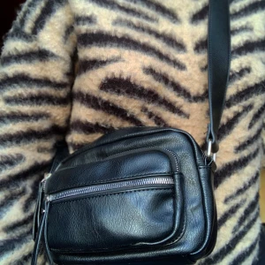 Axelremsväska  - Skitsnygg svart axelremsväska med massa fickor i perfekt att ha mobil, nycklar o mm då den rymmer mycket plats❣️ Frakt 50kr⚡️ Men kan även mötas upp