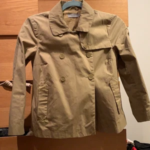 Trenchcoat från Cos  - Trenchcoat från märket COS, fint skick men har gått i sönder på ryggen men de går att laga. Kan skicka fler bilder vid intresse. Liten i storleken 