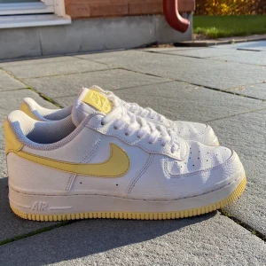 Nike Air Force 1 strl 38💜 - Säljer mina snygga Nike Air Force 1 med gula detaljer i strl 38 då jag tyvärr inte har användning av dom längre. De är använda ca 10 ggr, i bra skick, finns dock en liten fläck som man kan se på sista bilden, syns inte när man har på sig dom men går säkert att ta bort. Har inte bestämt pris än, men buda gärna i kommentarerna, budgivningen avslutas på onsdagen den 18 november. Frakt tillkommer💜