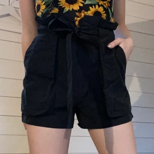 Svarta tygshorts från monki, strl 36 - Jättesköna högmidjade svarta shorts från monki med dragkedja, knapp samt ett band att knyta i midjan. Stora fickor!! 