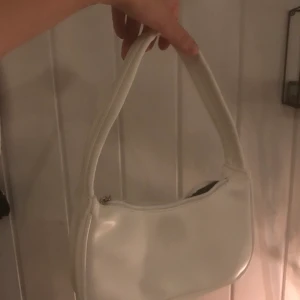 vit shoulder bag - vit liten shoulder bag i ett fejkläder material. aldrig använt den, insåg att jag hade för många väskor och behöver sälja. köparen står för frakt
