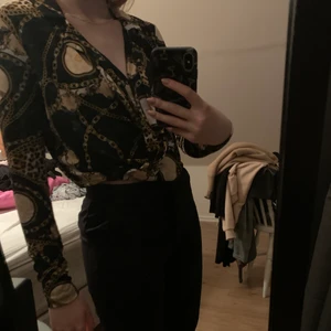 Mönstrad blus - Mönstrad blus från Gina Tricot. Använd 2-3 ggr men är i bra skick. Ganska djupt v-ringad, jag brukar använda en nål för att hålla ihop den lite mer. Det är en blus med kavaj detaljer.