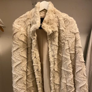 Pälsjacka (fake) - Beige medellång fake pälsjacka med mönster.
