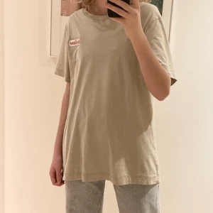 Oversized T-shirt från Weekday - Beige oversized t-shirt från Weekday. Trycket ”solar energy” på framsidan och ”24/7 hours” på baksidan. Använd ett par gånger men fortfarande i bra skick!