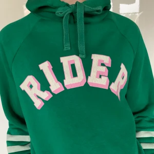Grön hoodie - Grön hoodie med text från gina tricot. Jättebekväm och så fin att ha lite oversized. Storlek M men personen på bilden har S i vanliga fall. Väl använd och mycket hållbar. Pris 50kr + frakt🌶