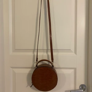 Rund väska  - En rund väska med två fack från hm. Fejkskinn. Föga använd.