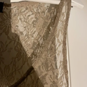 spetsklänning  - brun/brons-färgad spetsklänning. Bra skick, och snygg. Pris är disskuterbart och frakt spårbarfralt kan fixas.