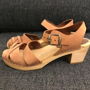  - Moheda BETTY Cognac svenska träskor med äkta läder. I bra skick endast en liten träbit lös som man ser i andra bilden. Nypris: 449:- säljes för 100:- Kan mötas upp på Södermalm/T-centralen eller skickas i Sverige. Köparen betalar för frakten. 