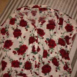 Blommig blus (nästan ny) - Använd 1gång runt högst 3h!) färg: röd vit och grön (blommig). Storlek: Small