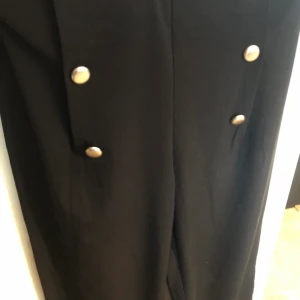 Kostym byxa från BikBok - Svart kostymbyxa från Bikbok med guldknappar som detaljer. Använd 4ggr, strl XL. Säljer för 90kr, pris går att diskutera.