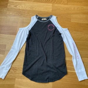 Långärmad tröja med hål på axlarna - En grå/vit långärmad tröja från Hollister med hål på axlarna. Strl XS. Pris: 30+frakt💗