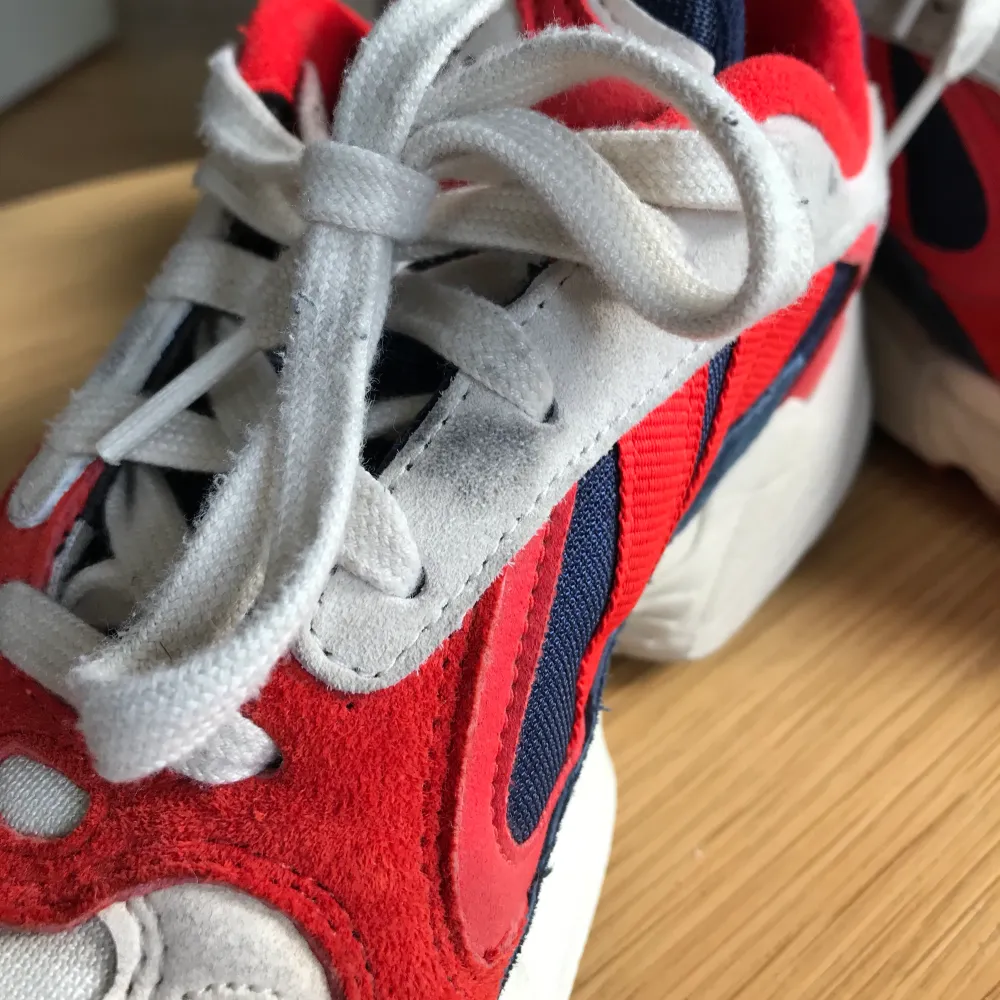 Sneakers från Adidas i modellen Yung-1. Röda, blåa och vita. Supersnygga men måste tyvärr sälja då jag insett att de är lite för små för mig :’( Väldigt sparsamt använda men ena skon har någon lite mindre fläck vid snörningen. Annars jättefina!!. Skor.