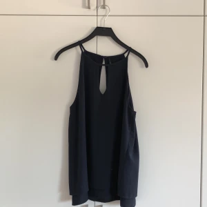 Linne/ Blus - Ett linne/ en blus i storlek 38. Öppen framtill och baktill. Dubbla tyg i ”fint” material. Extra knapp finns på lapp inuti.