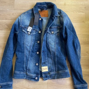 Replay jeansjacka strl. S Helt ny prislapp kvar.  - Helt ny, oanvänd jeansjacka från Replay Hyperflex modell. Inköpt för ca4 månader sedan men var för sen med att skicka tillbaka den. Kvitto och kartong finns kvar.  Nypris 1700kr. 
