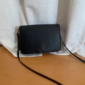 Simpel svart handväska  - Säljer en väldigt enkel och basic handväska från HM. Denna väska passar verkligen till allt och har ett avtagbart axelband om man vill sätta dit något lite roligare band. Köparen står för frakten💜