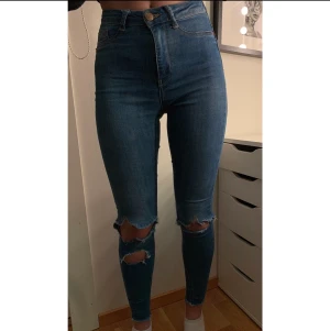 Blå jeans med hål - Fina jeans med hål på knäna. Relativt bra skick och har en tajt passform.