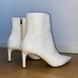 Vita klackar/boots - Supersnygga vita klackar/boots från H&M i ormskinnsmönster. Använda 1 kväll men har inte fått fler användningstillfällen än så för dem tyvärr. Superbekväma och inte alls svåra att gå i! 