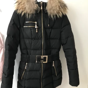 Hollies jacka - INTRESSEKOLL 🖤 vill se ifall det är någon som är intresserad. En riktigt varm och bekväm vinterjacka. Avtagbart bälte som sitter runt midjan med gulddetalj. Löstagbar äkta päls på luvan. Lång modell. Köpt för 4499kr förra vintern. I mycket fint skick, endast använd 1 vinter. Stl 34, passar även en 36 (jag har vanligtvis 36). Hör av er för info och bilder. Om många intresserade - budgivning