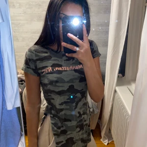 T Shirt kamouflage med slits - T Shirt komouflage med slits med text på. Storlek xs