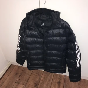 Adidasjacka dun - En adidasjacka i dun i storlek S, herrmodell men funkar både för tjejer och killar. Adidasmärket på vänster bröst bortslitet efter bara några få gånger därför täckt med svart övertäckningstejp. Skick 8/10. Pris kan diskuteras
