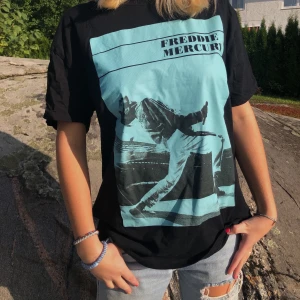 T-shirt med tryck - Cool t-shirt i svart med Freddie Mercury tryck i turkosblå från zara. I storlek M. Säljer pga att den inte kommit till användning så den är använd 1-2 ggr. Köparen står för frakt. 