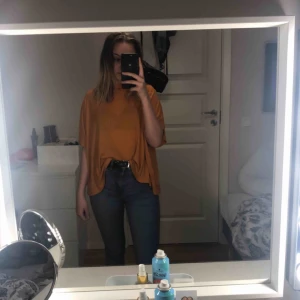  - En gul/orange blus som e luftig och skön/mjuk, den har som ett snitt på baksidan 