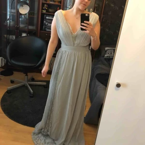  - Oanvänd balklänning! Säljer pga att jag hittat en annan. Superfina spetsdetaljer upptill, baktill och nertill i en slits. Extra lång modell och gömd dragkedja baktill.