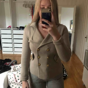  - Jätte fin jacka/kofta i stickat material. Sitter tajt mot kroppen och ger en fin figur. Knapparna är i guld färg.  Och plagget i beige/grå
