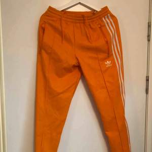 Fräsch orange Adidas tracksuit-byxor i storlek M! Använd 1 gång! Nypris ligger på 700kr. Kan mötas upp eller köra på frakt. Frakt ligger dock på köpare.