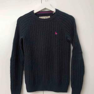 Marinblå, kabelstickad tröja med rosa märke från Jack Wills. Storlek UK 8 vilket motsvarar 36 i EU. 