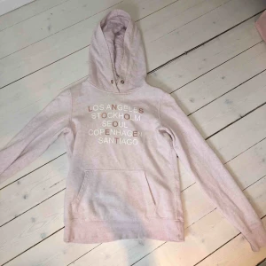 - Ljusrosa hoodie från HM med städer tryckta i vit och roseguld. Storlek XS men passar även S, jättebra skick. Snöret i luvan fattas tyvärr. Köpt för 300 kr ungefär