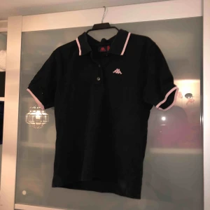  - Kappa piké, står medium men passar mer som en small. Svart med rosa detaljer