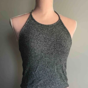  - Gråmelerad halterneck linne med knytning från Brandy Melville. Använd fåtal ggr. Ordinarie pris 180kr. Köparen står för frakt