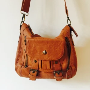  - Ljusbrun väska, reglerbart axelband. Flera olika fack utanför och inuti. 