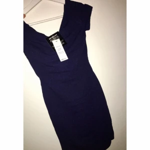  - En marinblå klänning med korsade band i ryggen, köpt ifrån Nelly.com för ett tag sedan. Aldrig använd & har lapparna kvar. Har silikon rem runt om och glider därför inte ner vid brösten.  Kan mötas upp eller så får köparen stå för frakt!