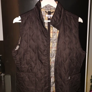 Burberry-inspirerad Väst - Fin brun väst inspirerad av burberry. Använt max 2 ggr. Köpt second hand men är i nyskick. I storlek M och passar både M och S. 