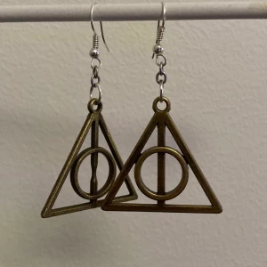 Örhängen, Harry Potter - Coola Harry Potter örhängen i form av dödsrelik’s symbolen!                                                                         Har 3 styckwn (ej par)! 46 kr inkl frakt för två stycken samt 24 inkl frakt för endast en.                                           Hör endast av dig om du är intresserad av att köpa! Tack på förhand :).                                                        Endast ett örhänge kvar!!!