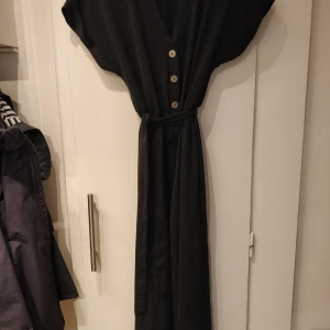Svart jumpsuit  - Fint skick! Fin v-urringning med knappar, croppade ben, och ett knytband. Storlek 38, passar bäst för S eller M. Kan mötas i Stockholm eller skicka mot fraktkostnad ✨