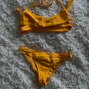 Gul/orange bikini - Säljer denna superfina bikini då jag endast använt underdelen en gång (den kommer helt enkelt inte till andvändning). Beställde den från NA-KD för ca två år sedan. Mycket bra skick och tvättad🧼! Köpte står för frakt 📦 