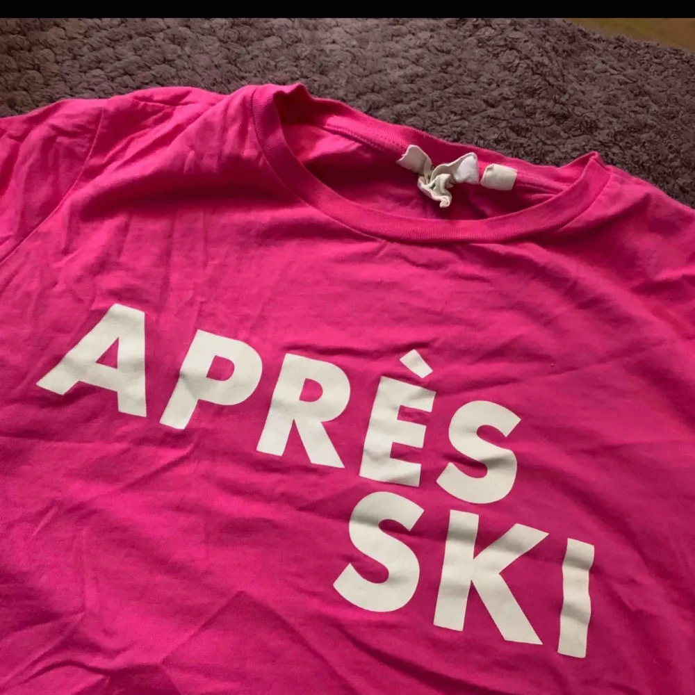 Cerise/skrikrosa T-shirt med texten ”Après ski”. Storlek XS från H&M. Endast använd hemma en gång eftersom jag har minst 50 andra t-shirts. Väldigt bra skick 💕. T-shirts.