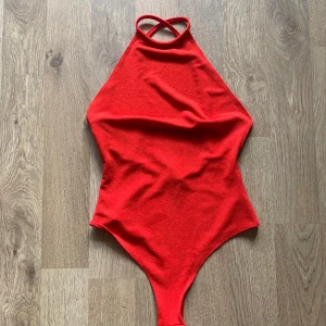 Röd Body med öppen rygg - Säljer en röd body med öppen rygg från Nelly. Helt oanvänd i storlek s. 100kr (+ frakt som köparen står för). 