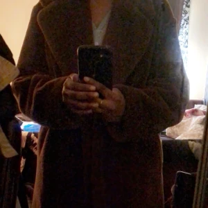 En lång kappa från hm.  - En lång brun kappa från HM. Jätte skön till höst/vinter!