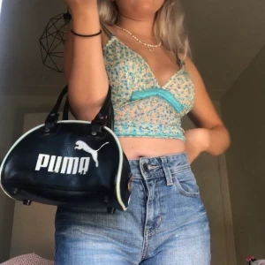 svart PUMA mini väska - vintage puma mini väska 🥺 så söt och 2000-talet !! liknar von dutch väska! det är vegan läder och känns så mjukt och snyggt!  påsen är i vintage skick och bokstäverna kan lätt röra upp lite med lite vit färg!!            lämna ett bud