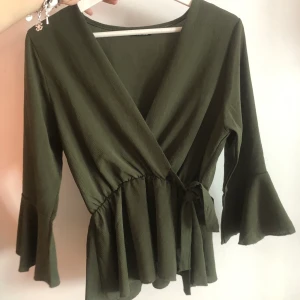 Blus  - Olivgrön topp med knytning fram. Storlek S-M. Köparen står för frakt men kan även mötas upp i Gbg.