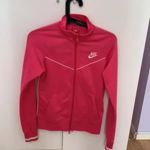Nike rosa träningszip tröja - Använt skick därav priset. Storlek L 168cm (BARNSTORLEK, se bild 3). Köpt för ca 350kr. Pris kan diskuteras frakt tillkommer, skriv vid intresse!