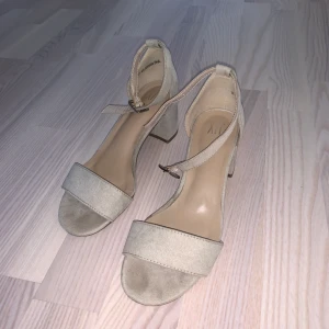Låga klackar från Nelly - Låga ”low block heel sandals” från Nelly. Färgen är beige och dem är använda en kväll inomhus under en bal middag. Fint skick. Strl 37 men jag har 38/39 vanligtvis.  50 kr + 66 kr frakt 