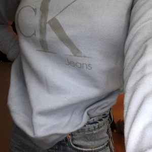 Blå CK - Detta är en ljusblå Calvin Klein tröja som håller en varm som går ihop till så mycket och går att styla med en skjorta under till byxor och kjol!