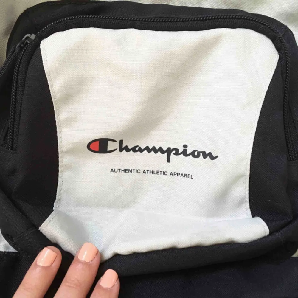 En fin liten ryggsäck från Champion, 90-tal. Den är vit med mörkblå detaljer. Har en pyyyytteliten rosa fläck (se bild 2) men det är verkligen inget man ser om man inte kollar noga. Annars i jättebra skick!. Väskor.